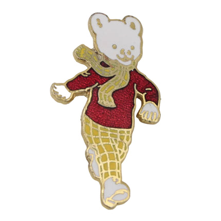 A small Rupert bear enamel pin with gold-tone metal outlines, featuring a white face and paws, a red sweater, and yellow-and-white checkered pants, shown on a plain light background.