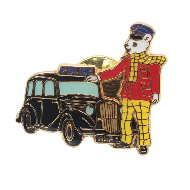 An enamel pin depicting a London cab with a bear driver wearing a red and yellow checkered uniform, set against a plain white background.