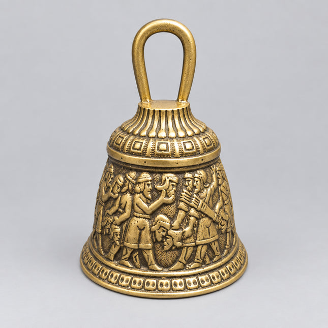 An antique-style metal bell with an embossed classical scene on the front and a loop handle on top, set against a solid green background.