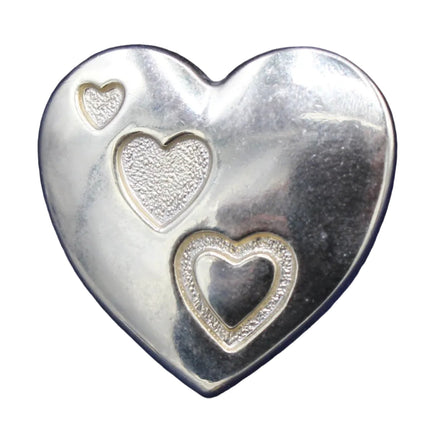 Silver heart-shaped object with cut-out heart designs on a white background