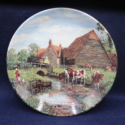 Decorative plate with a rural scene featuring cows and a house.