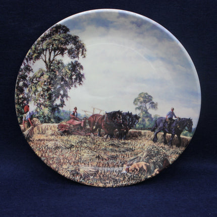 Decorative plate with a rural scene of people and horses in a field on a dark blue background