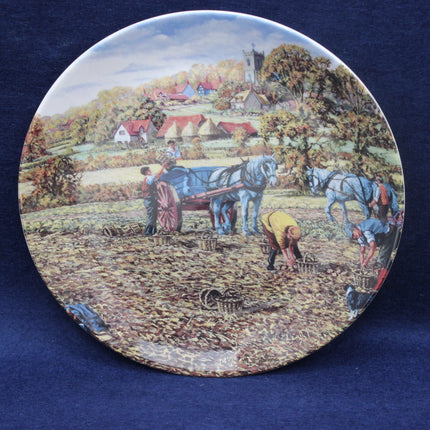 Decorative plate with a rural scene of people working in a field with horses.