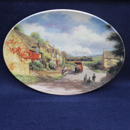 Decorative plate with a rural scene featuring a village street, houses, and a horse-drawn carriage.