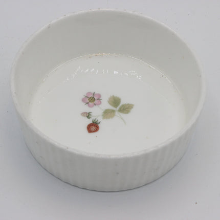A white ceramic ramekin with a fluted rim, decorated with a small hand-painted strawberry and flower motif in the center.