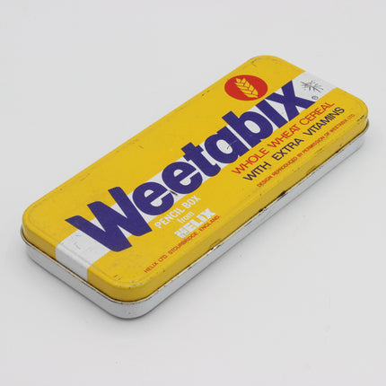 A vintage yellow Weetabix Pencil Box tin for Weetabix Whole Wheat Oatmeal with extra vitamins, featuring bold blue lettering and a white background.