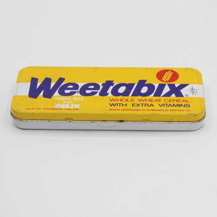 A vintage yellow Weetabix Pencil Box tin for whole wheat cereal with extra vitamins, featuring bold purple branding and a small red wheat logo, photographed on a white background.