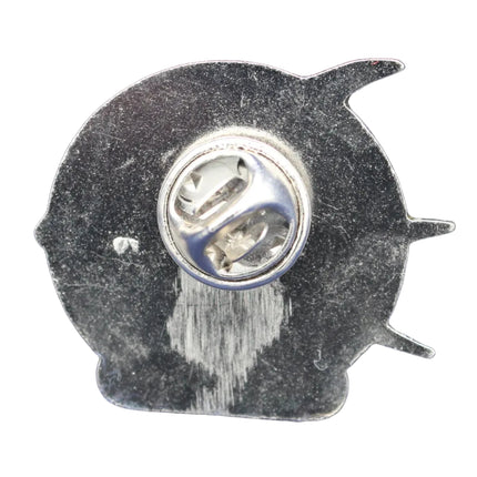 Metallic pin with a fish-shaped back on a blue textured background