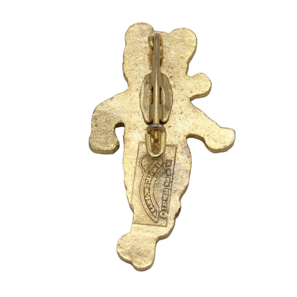 A gold-colored metal pin shaped like a stylized bear, showing the back side with a lobster clasp and a stamped maker's mark, set against a plain light gray background.