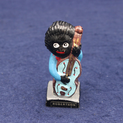 Figurine of a golliwog holding a cello on a blue background