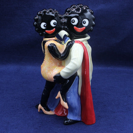 Figurine of two Gollies embracing on a blue background