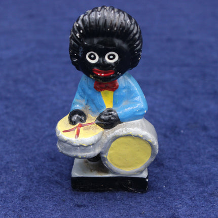 Figurine of a person with a black hairstyle playing drums on a blue background
