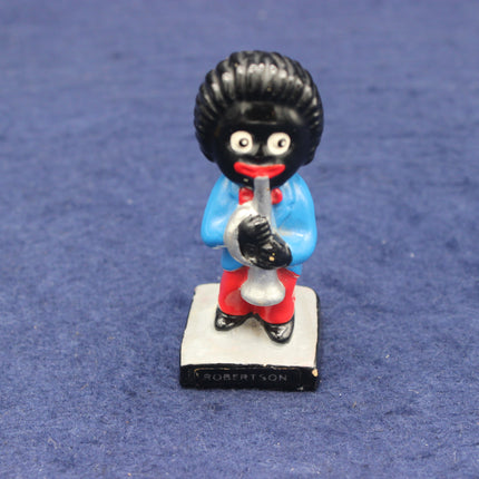 Figurine of a character with a black topknot, blue shirt, and red pants on a blue background.