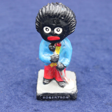 Golliwog figurine with a blue outfit and red shoes on a blue background