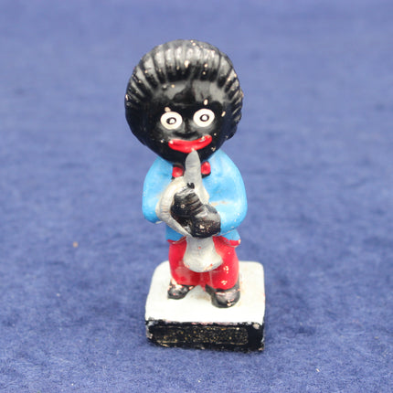 Figurine of a character with black hair, blue shirt, red pants, and white shoes on a blue background