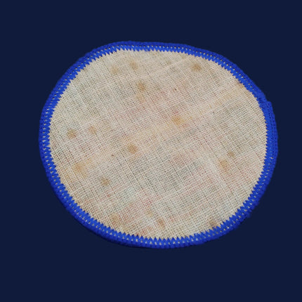 Round beige fabric patch with blue border on a dark background