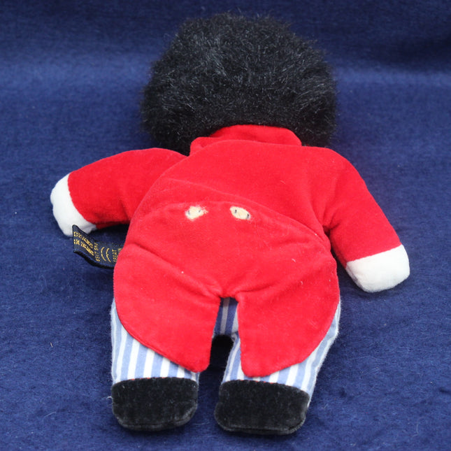 bean filled vintage golly doll in a red tunic on a dark blue background