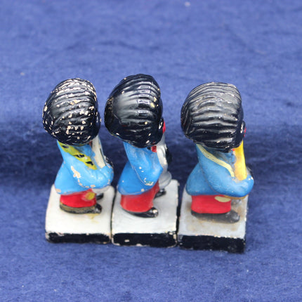 Three small Golly figurines with colorful outfits and black hats on a blue background
