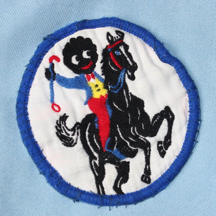 Embroidered patch of a Golly on a horse with a blue border on a light blue background