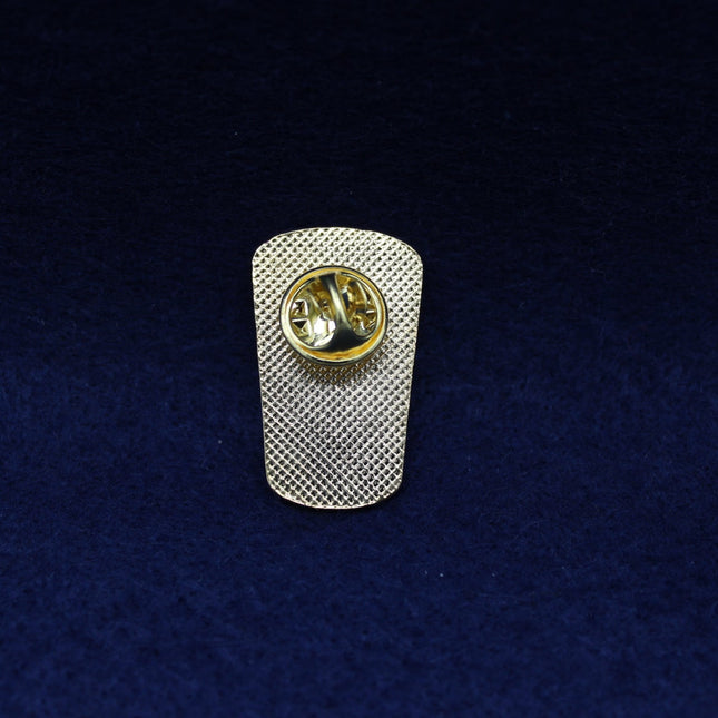 Metallic Guiness badge with a circular clasp on a textured blue background