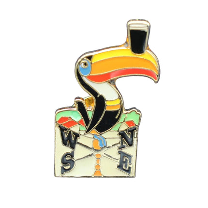 Colorful toucan-shaped compass pin on a blue textured background