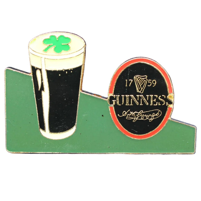 Guinness beer glass with shamrock on a green base against a blue background