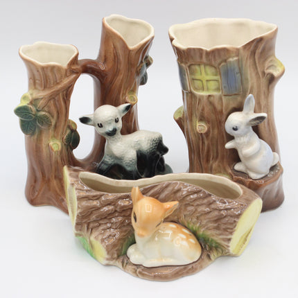A ceramic woodland-themed vases shaped like tree stumps and logs, featuring a white lamb, a white rabbit, and a small orange-brown fox figurine, photographed on a white background.
