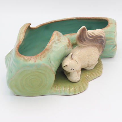 A ceramic planter shaped like a squirrellwith a small beige squirrel figurine sitting beside it, photographed on a plain white background.