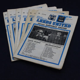 Stack of Leeds United United football match programs on a dark background