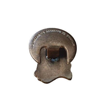 A vintage metal badge with engraved text reading MILLER 