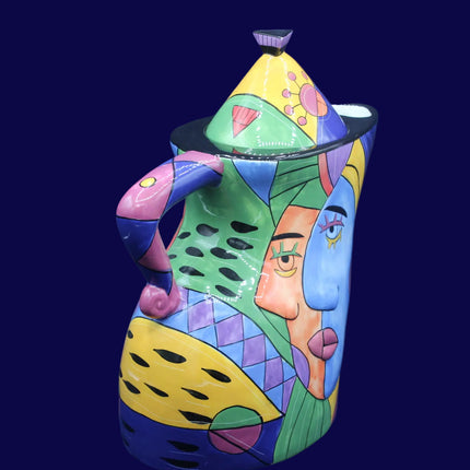 Colorful ceramic teapot with abstract face design on a dark blue background