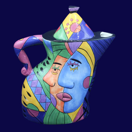 Colorful ceramic teapot with artistic face design on a blue background