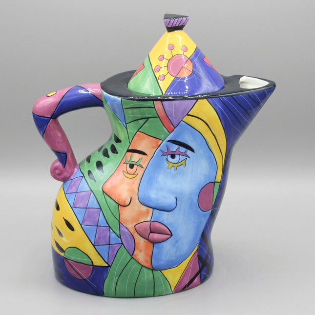Colorful ceramic teapot with artistic face design on a blue background