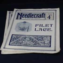 Stack of 'Needlecraft' magazines on a black background
