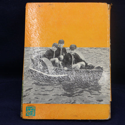 Book cover with illustration of three children in a boat on water, against an orange background.