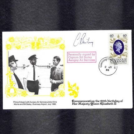 A commemorative Guernsey airmail first-day cover envelope featuring a black-and-white photo of Prince Edward with Aurigny Air Services pilots, a yellow ornamental border, a Queen Elizabeth II stamp, and signatures on a black background.