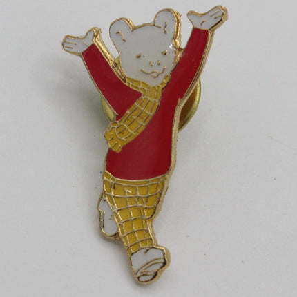 A small enamel pin shaped like a white bear wearing a red outfit and yellow checkered pants, standing on a plain light background.
