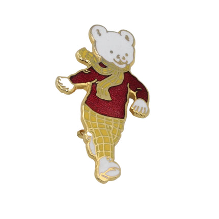 A small enamel pin of Rupert Bear wearing a red sweater and yellow checkered pants, shown on a plain white background.