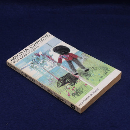 Book titled 'Ten Little Niggers' by Agatha Christie on a dark blue background