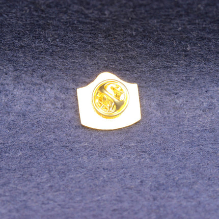 Gold theakston mild enamel emblem on a textured blue background