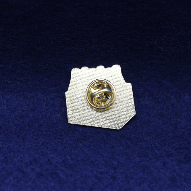 Coca Cola Pin badge with gold center and white base on a blue textured background