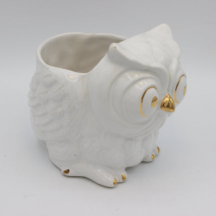 A white ceramic owl-shaped planter with gold accents on its eyes, beak, and feet, set against a plain white background.