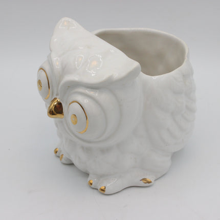 A white ceramic owl-shaped planter with gold accents on its eyes, beak, and feet, set against a plain light gray background.
